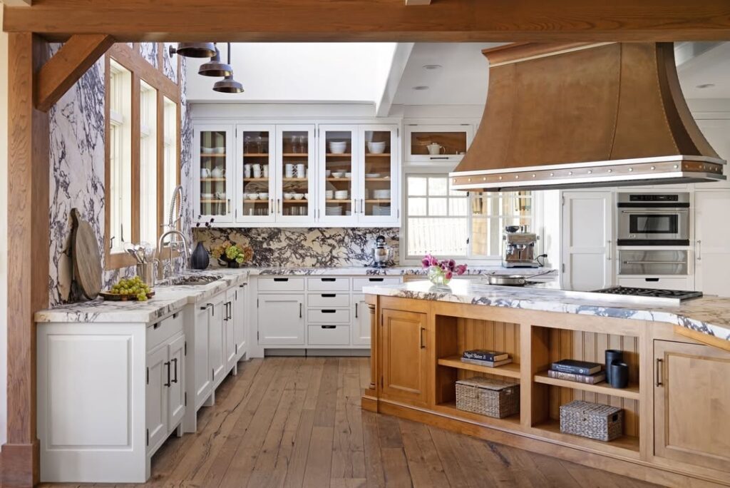  White kitchen with marble backsplash wooden accents and copper hood