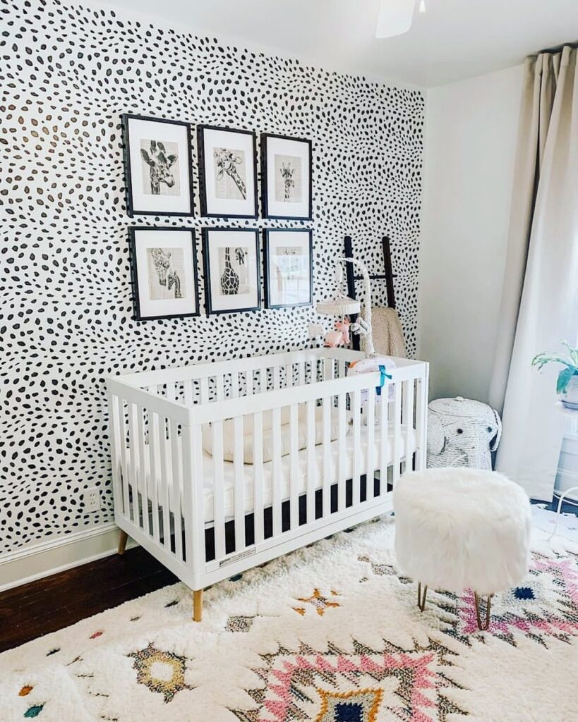 Black and white nursery with spotted wallpaper giraffe prints and geometric rug