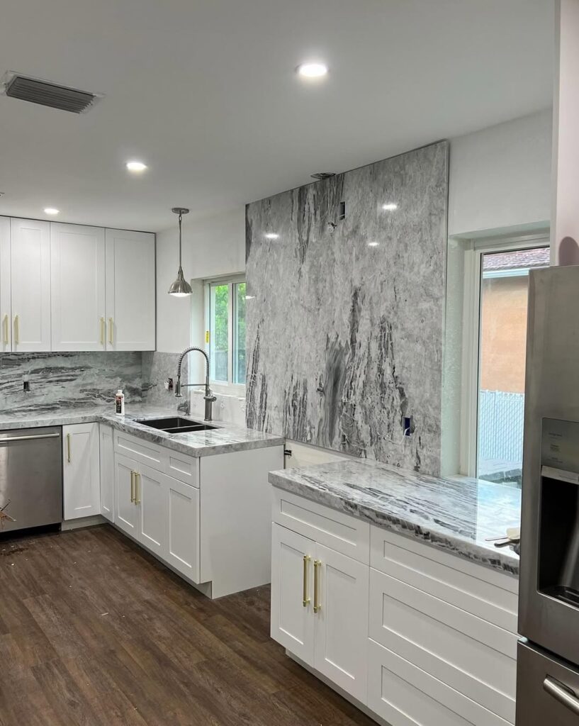 White modern kitchen with gray marble backsplash and golden hardware