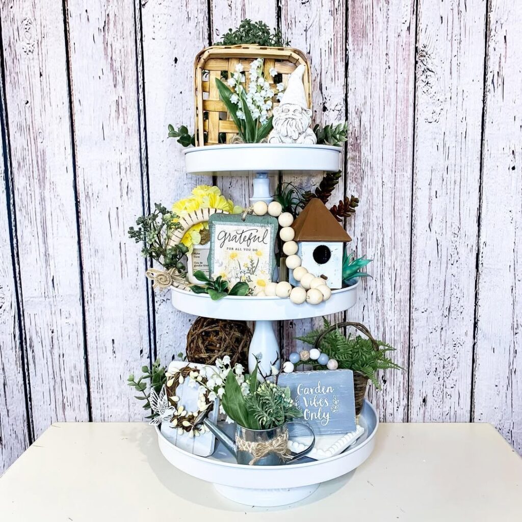 White tiered tray styled with garden decor flowers and wooden accessories