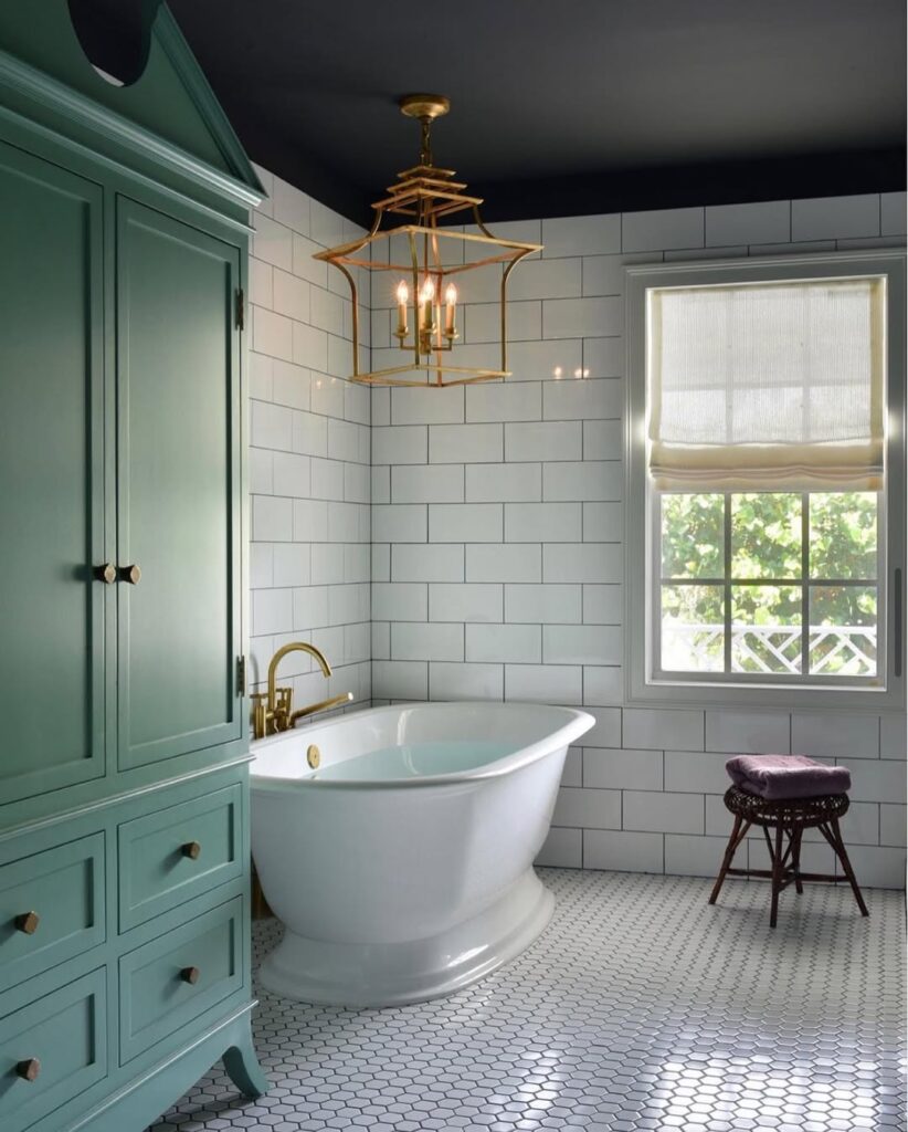 Green bathroom with white subway tiles and brass fixtures