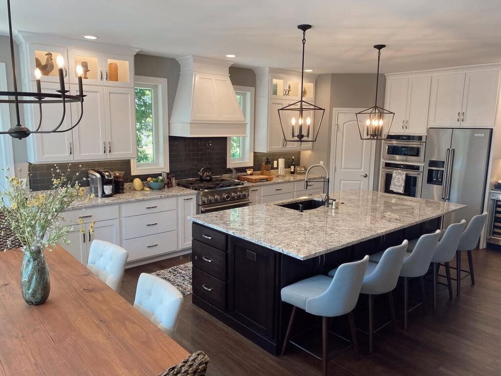 Kitchen with black island white cabinets and granite countertops