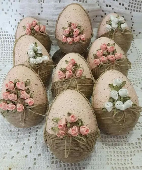 Nine decorative eggs wrapped in twine with pink and white roses