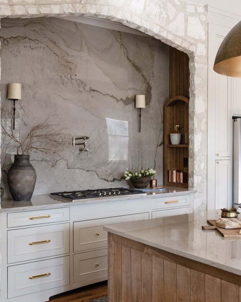 Kitchen alcove with textured stone wall white cabinets and brass hardware