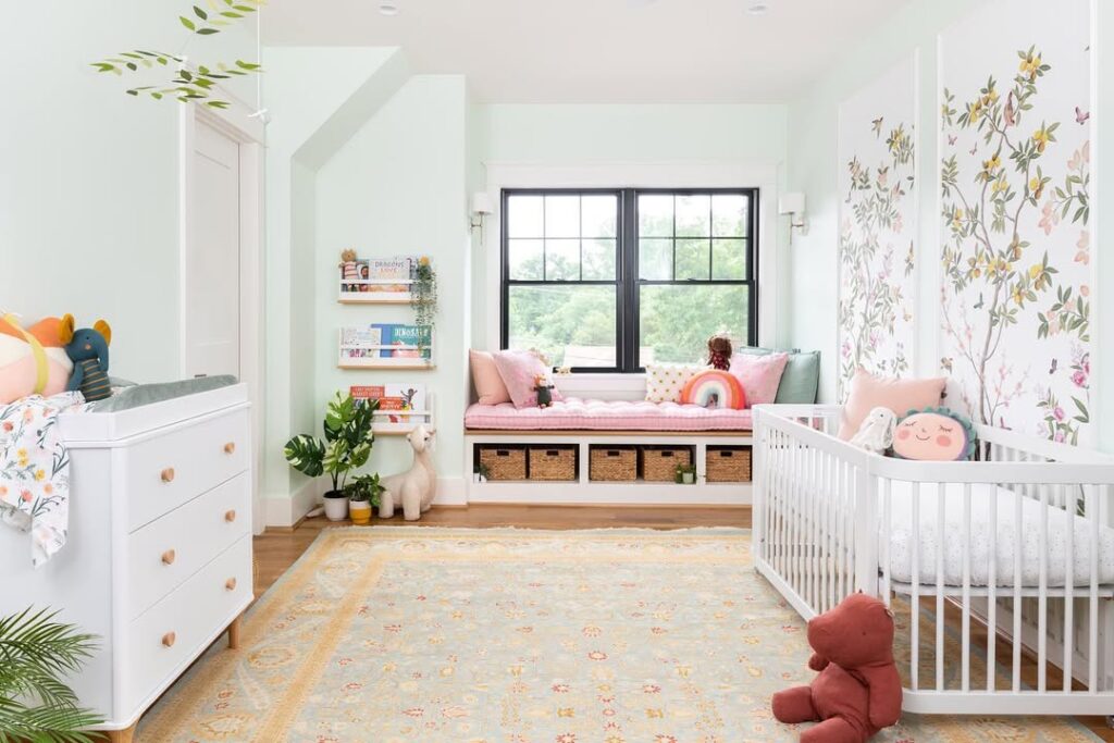 Nursery with window seat reading nook white dresser and floral wallpaper accent wall