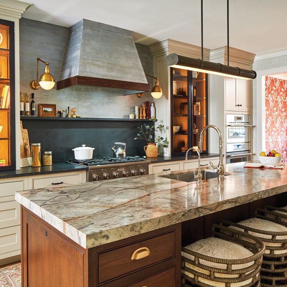 Kitchen with copper hood marble counters and industrial lighting