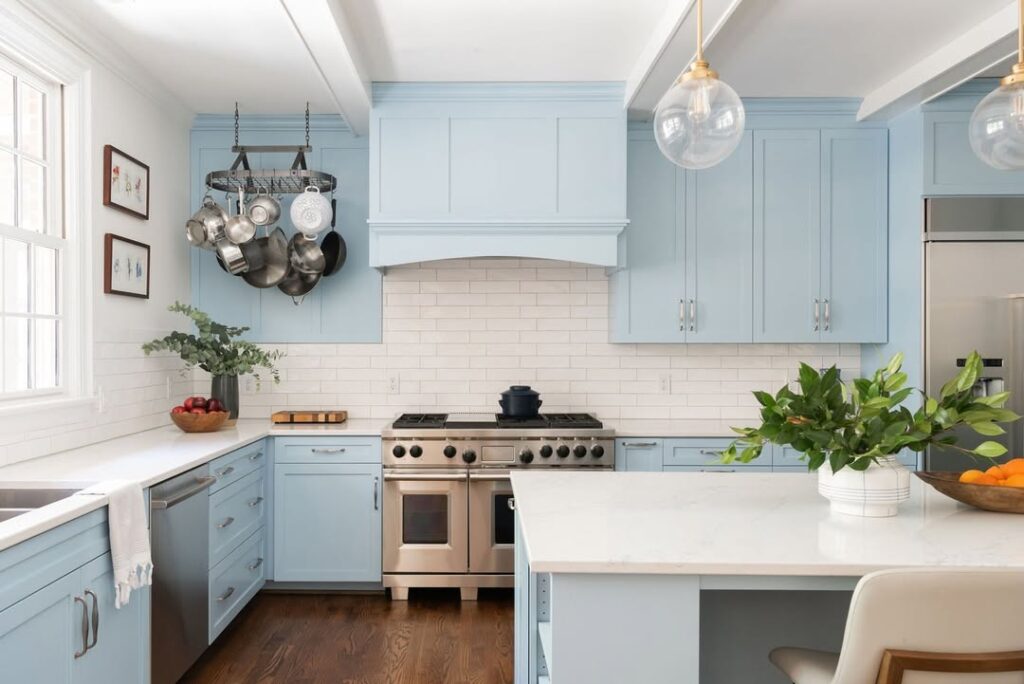 Light blue kitchen with pot rack white countertops and stainless appliances