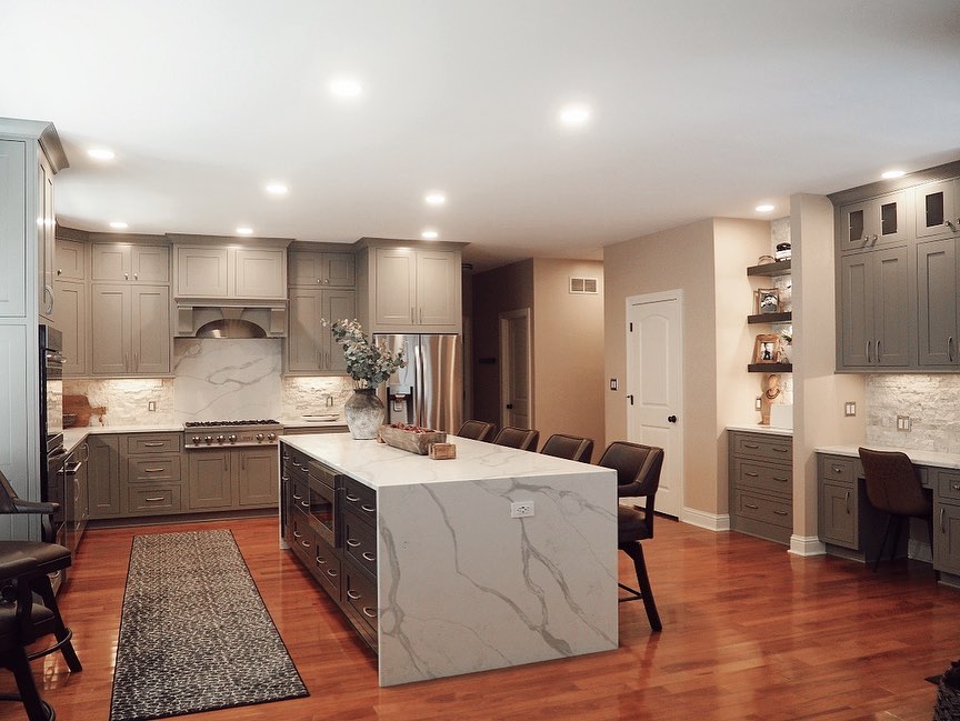 Grey kitchen with marble waterfall island and wood floors