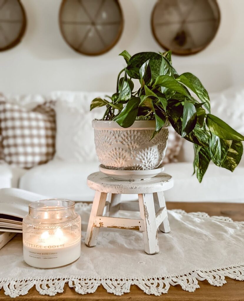 White stool with potted plant candle and lace tablecloth arrangement