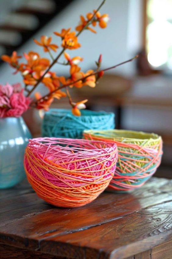 Three colorful string wrapped bowls with orange flowers