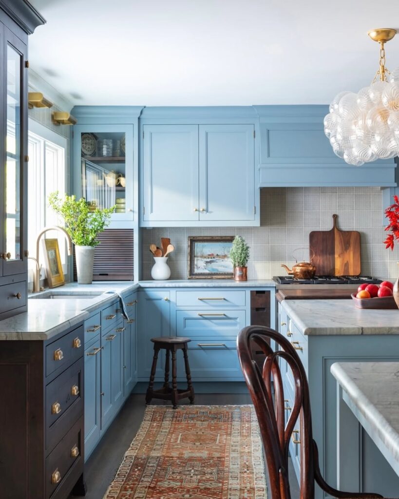 Blue kitchen with bubble chandelier marble counters and oriental rug